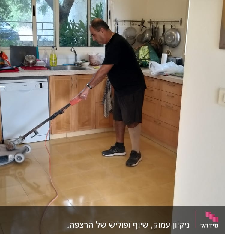 אדם מנקה רצפה עם מכונת פוליש במטבח